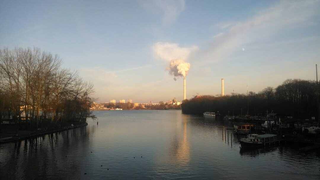 Industrial chimney releasing smoke near a river